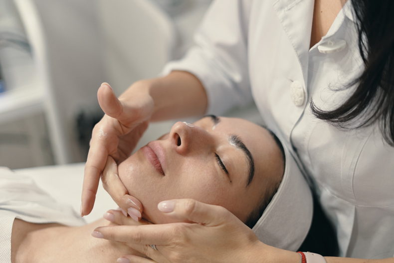 Esthetician applying cream during facial treatment